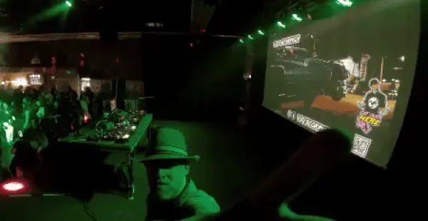 Ein Mann mit Hut zeigt in eine Kamera.